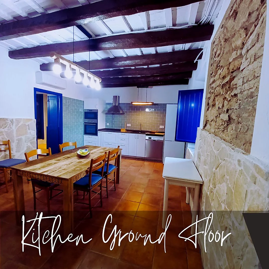 Ground floor kitchen with original stone walls, wooden ceiling beams and modern appliances at Masia St Salvador 1582