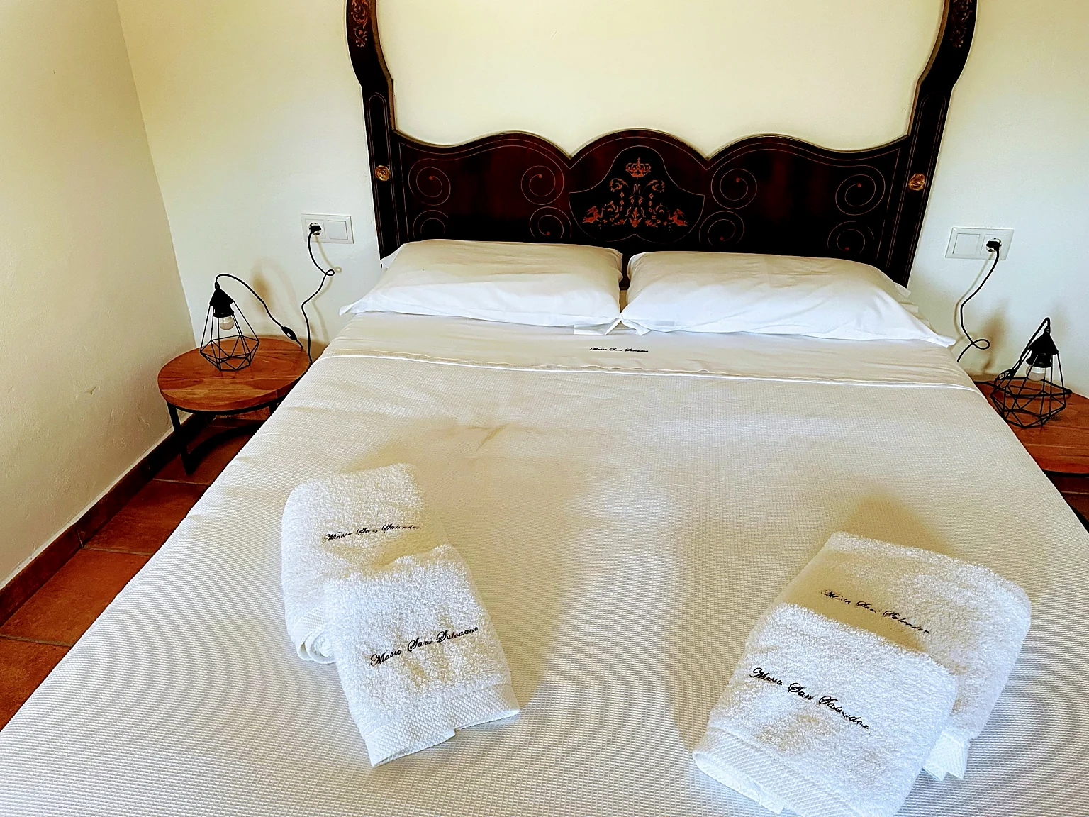 Double bedroom with ornate antique headboard and branded towels at Masia St Salvador 1582 holiday rental