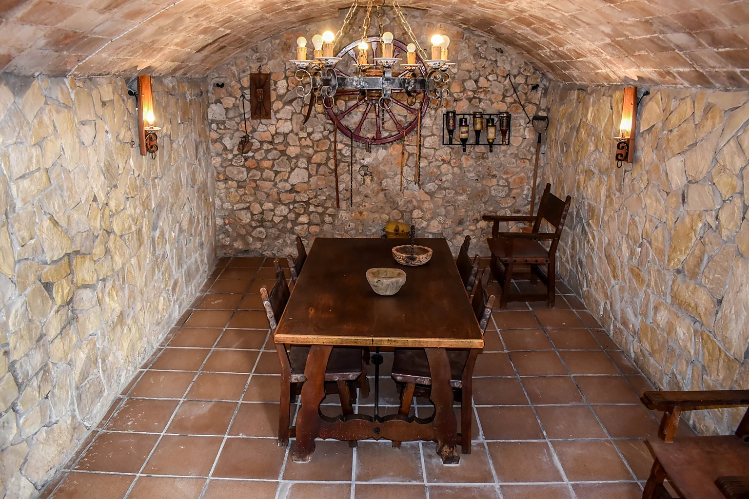 Historic stone wine cellar with vaulted ceiling, rustic dining table and wrought-iron chandelier
